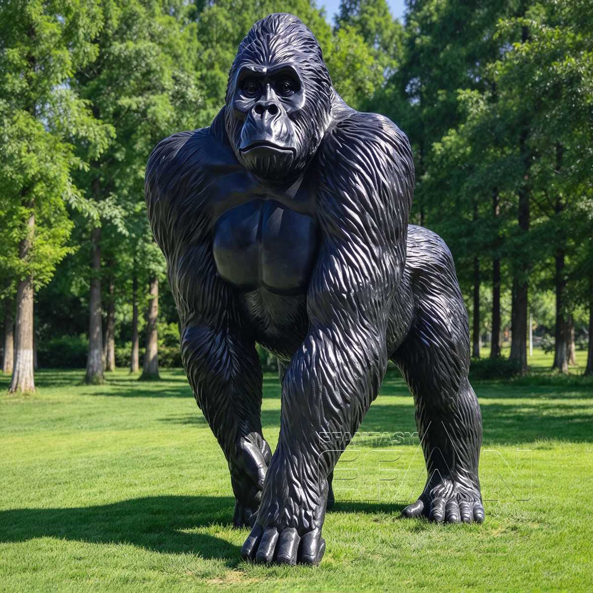 Black bronze gorilla sculpture standing on grass among trees