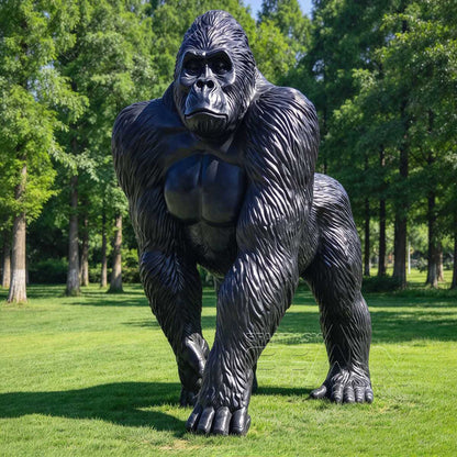 Black bronze gorilla sculpture standing on grass among trees