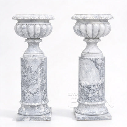 Two white and gray marble urn planters with fluted bowls and cylindrical pedestals on a white background