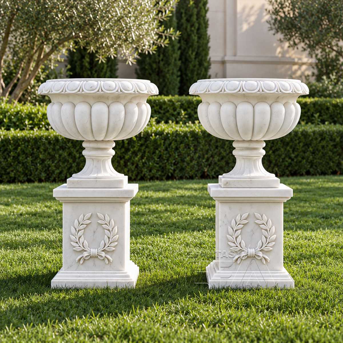 Pair of white marble urn planters with laurel wreath pedestals in an estate garden