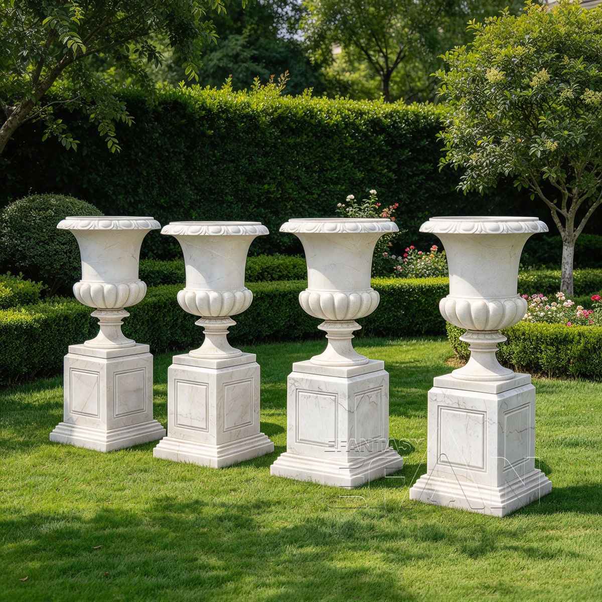 Four white marble flower pots with square pedestals arranged in a garden