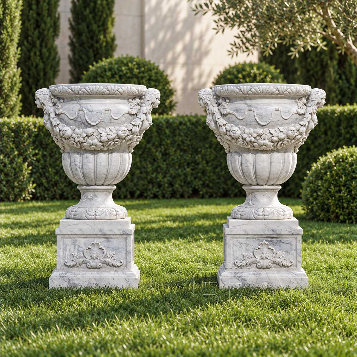 Pair of white marble urn planters with floral garland reliefs in a formal garden