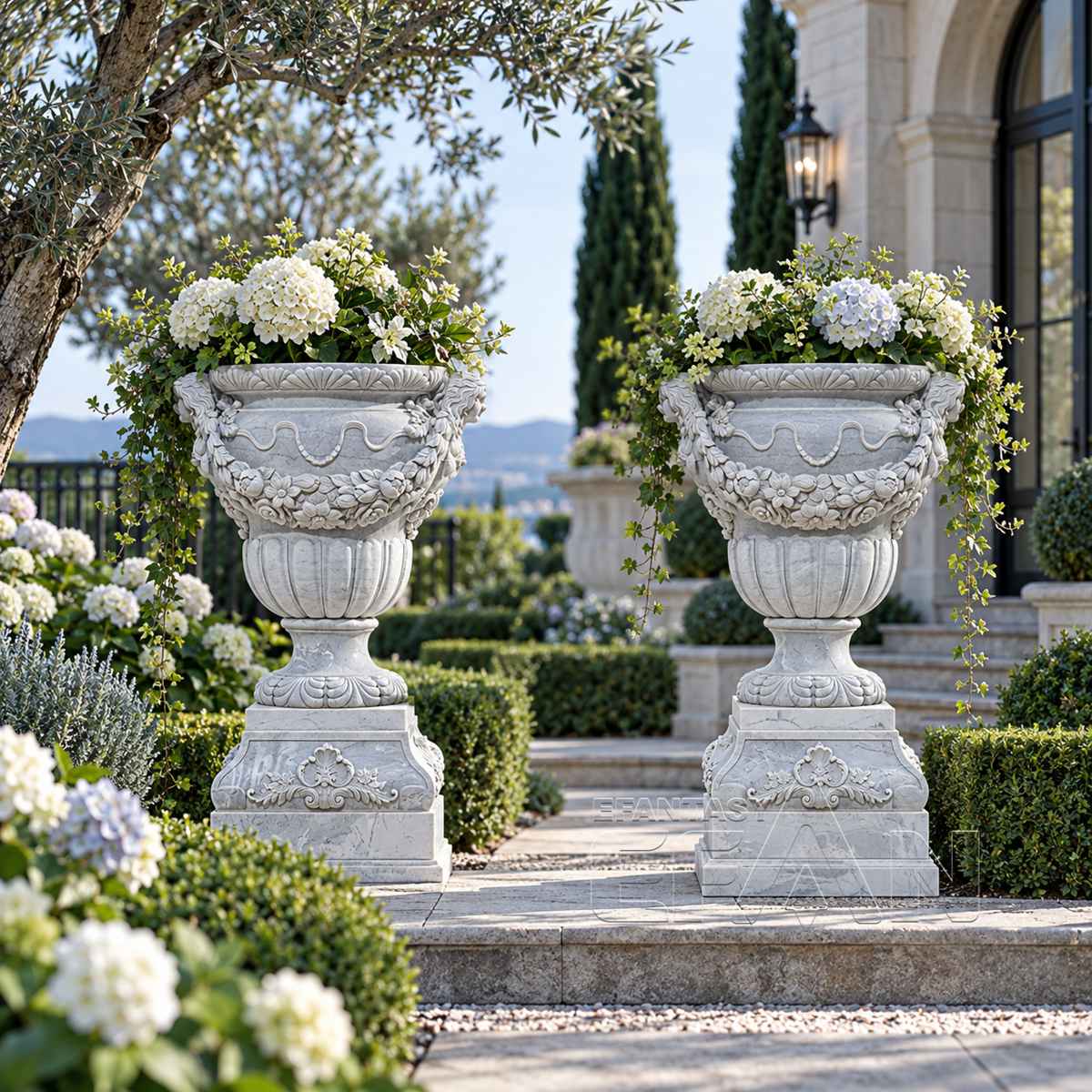 Two white marble relief planters holding white flowers beside an estate terrace